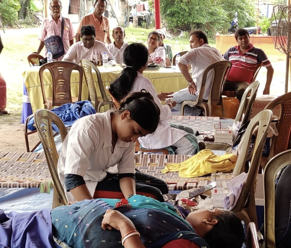 Pre-donation screening at the Anubhav CMC counter — fasting/random sugar from a single fingerprick. — Golabari blood donation camp