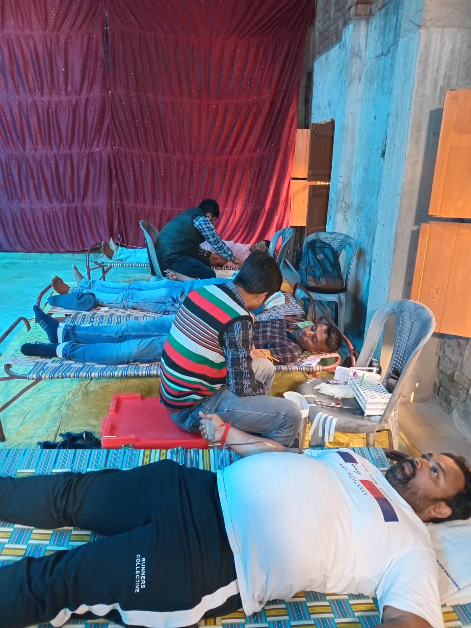 Volunteers laying out the bed grid and setting tube trays before donors arrive. — Santoshpur blood donation camp