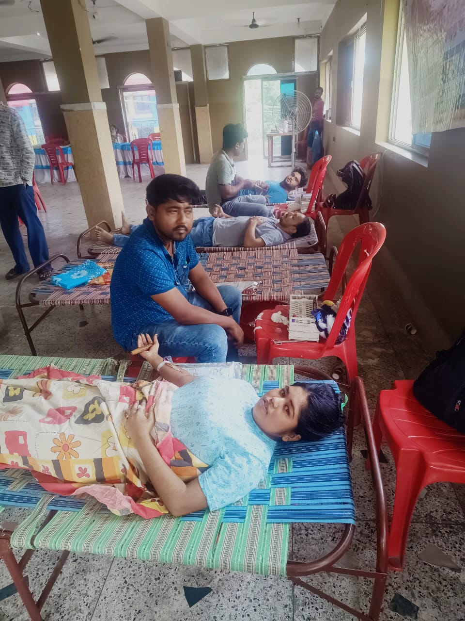 Phlebotomist prepping the arm — antiseptic wipe, vein found. — Ghola blood donation camp