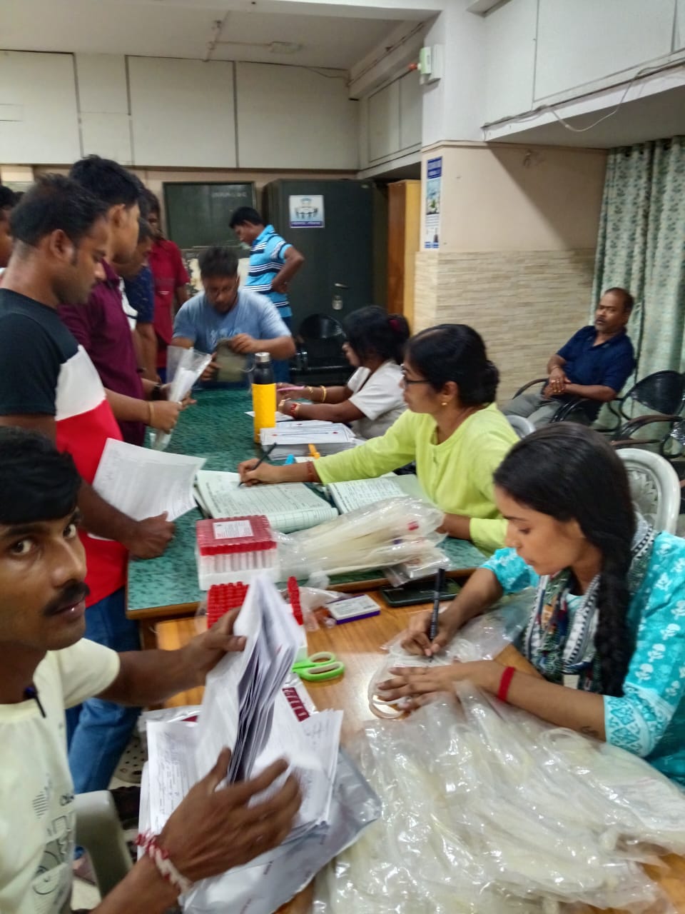 Registration desk at the front — donor cards being filled out as the queue builds. — Habra blood donation camp