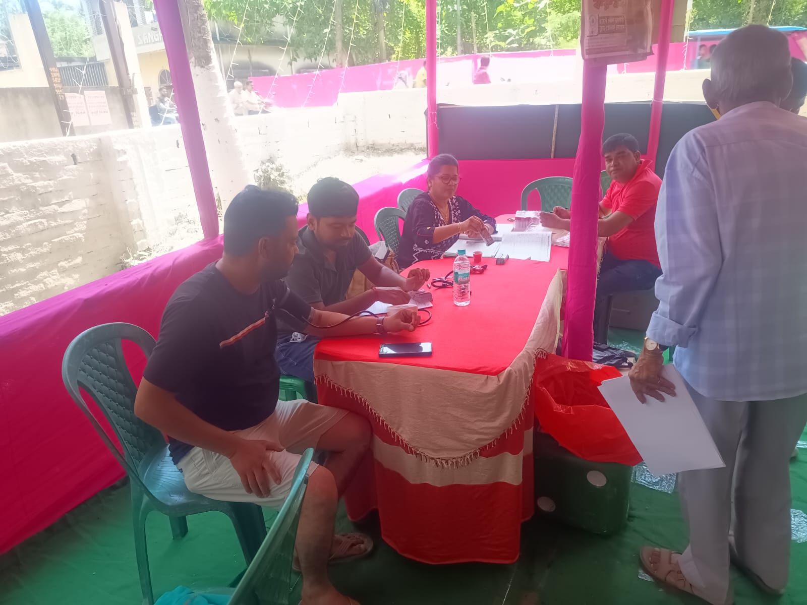 Anubhav CMC desk running back-to-back screenings — sugar, hemoglobin, BIA for every donor in queue. — Amdanga blood donation camp