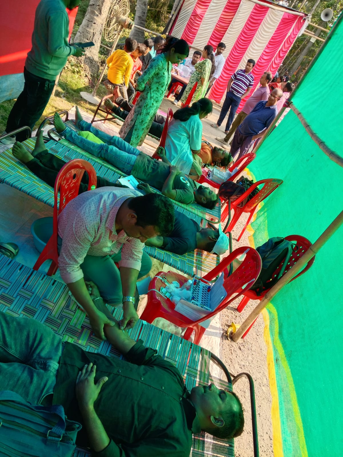 Mid-camp throughput: multiple beds running, attendants rotating. — Birati blood donation camp